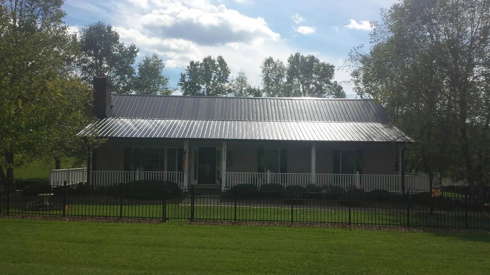 Gray metal roof on a brick ranch with a full width front porch — Gutter Guard Installation work by our crew in Stitzer
