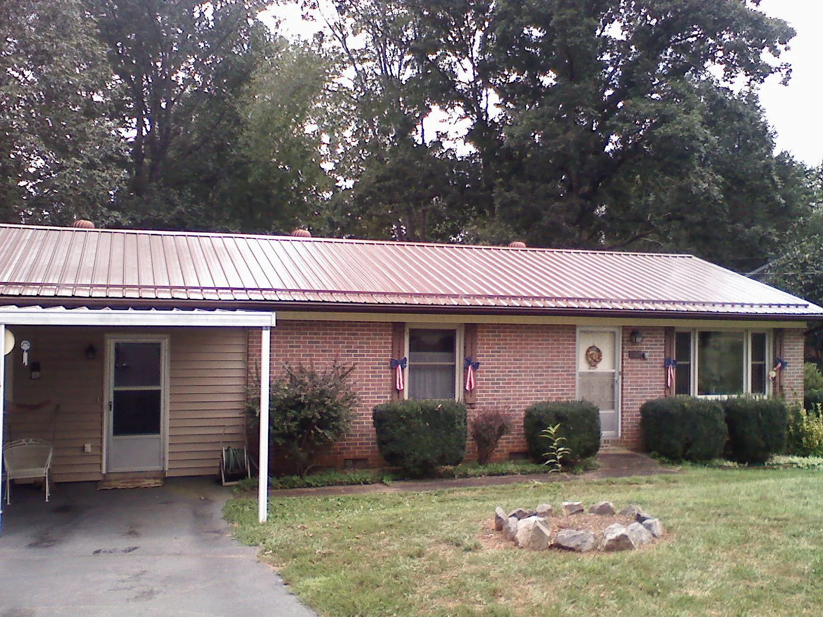 Bronze metal roof and carport on a brick ranch home — Roof Repair work by our crew in Stitzer