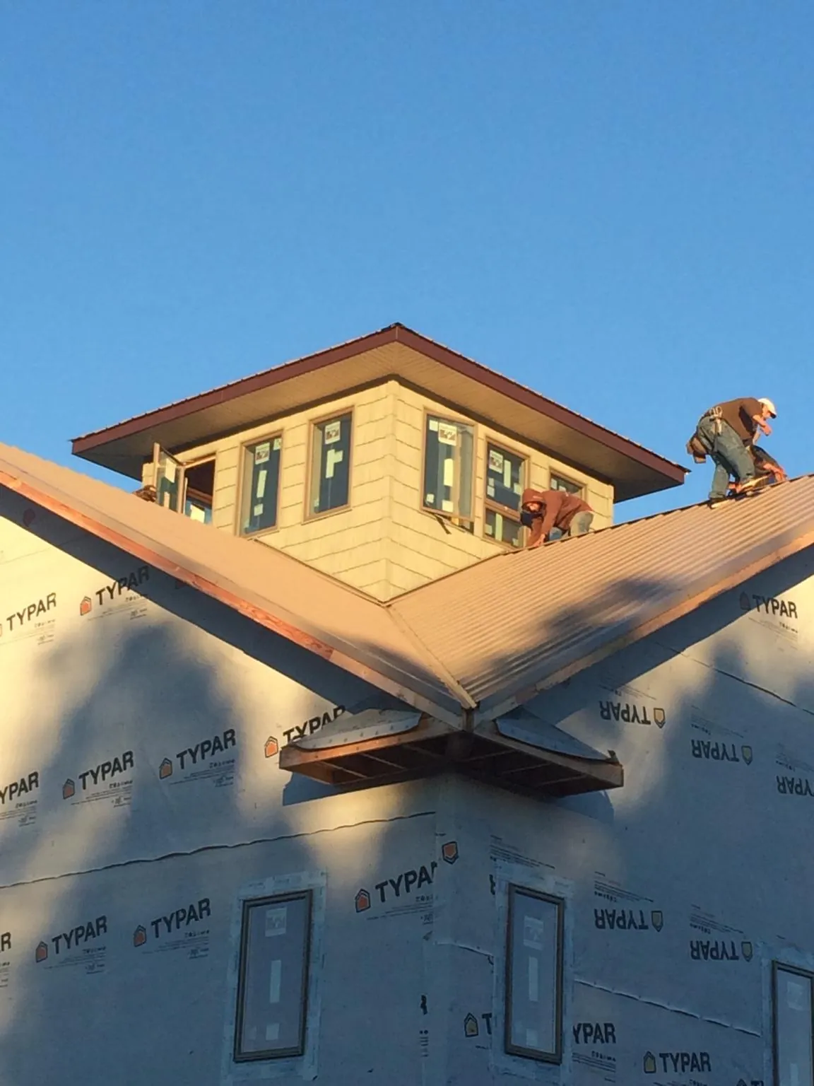 Roofers working around a rooftop cupola on a new metal roof at sunset — Roof Waterproofing in Stitzer by Roofing Brothers